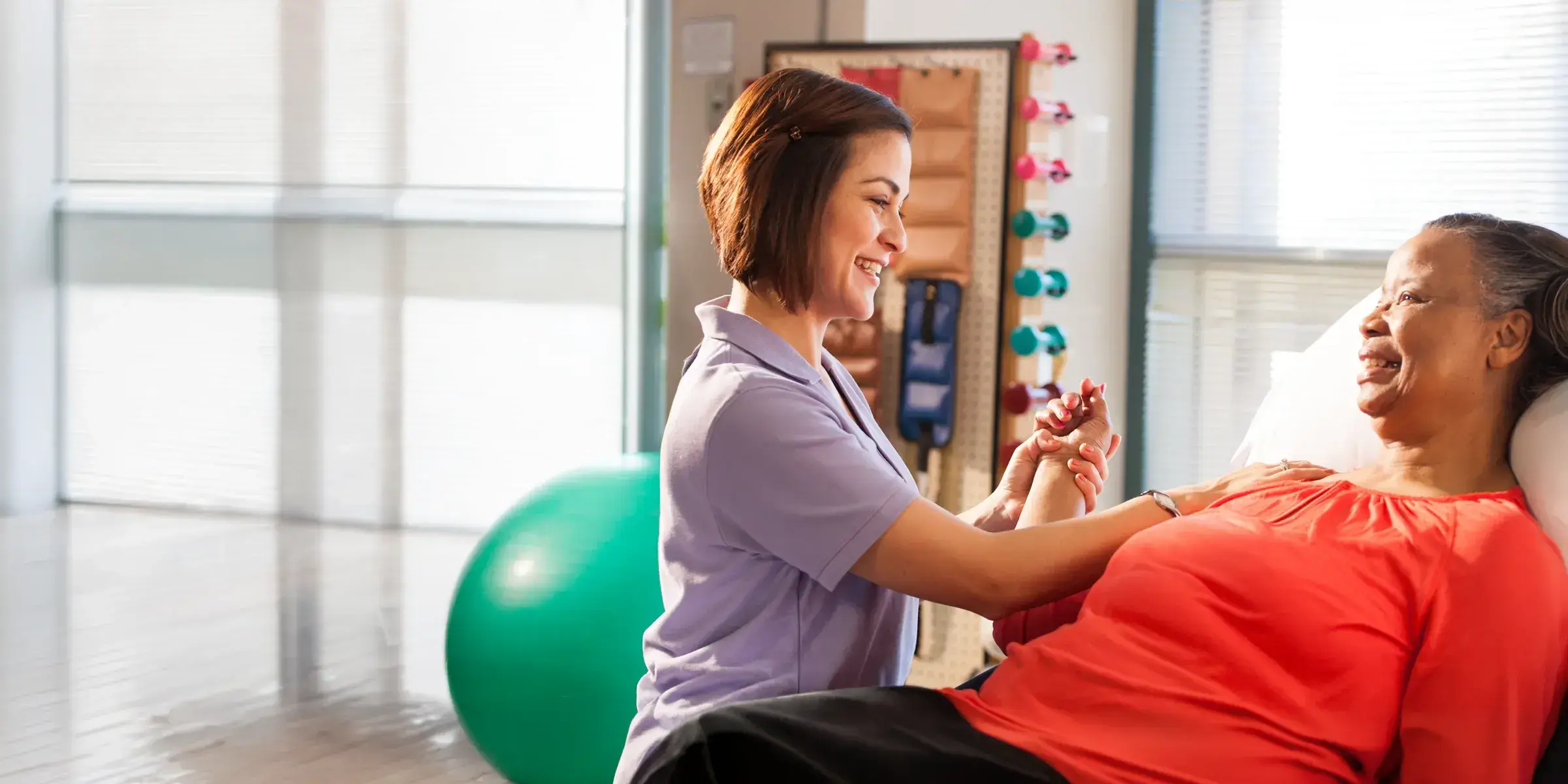 therapist works with patient in gym